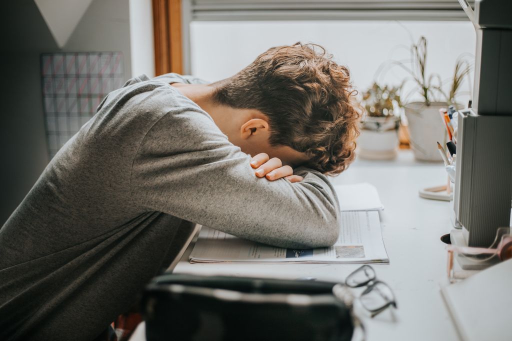 tired student resting on pile of books