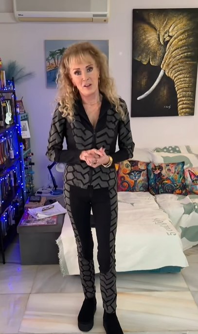 Beverley in black gym set standing in living room