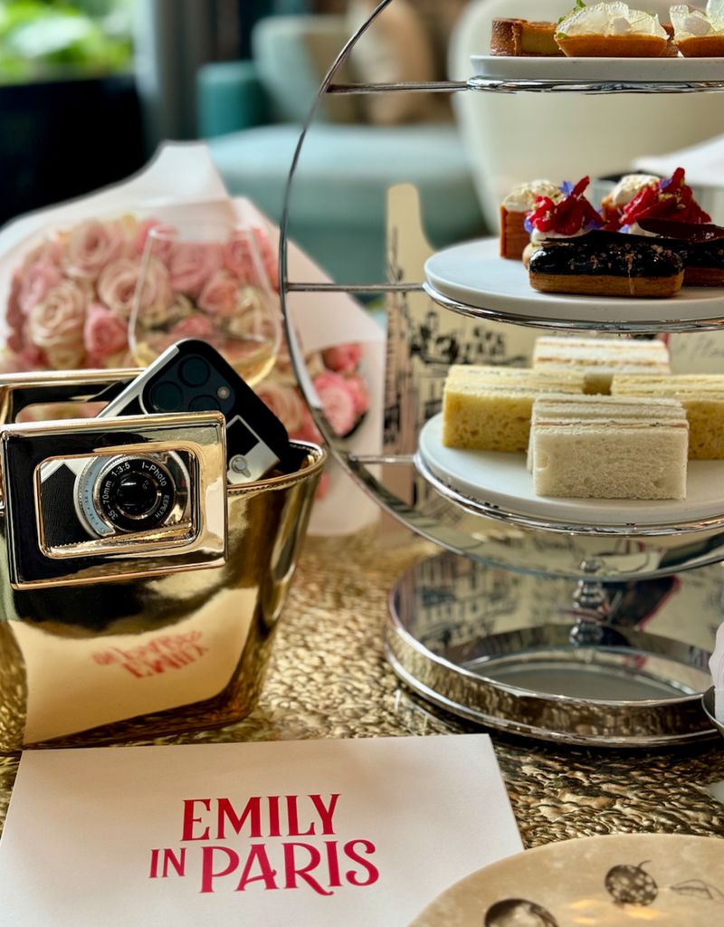 afternoon tea on a table with camera and an envelope with the words Emily in Paris