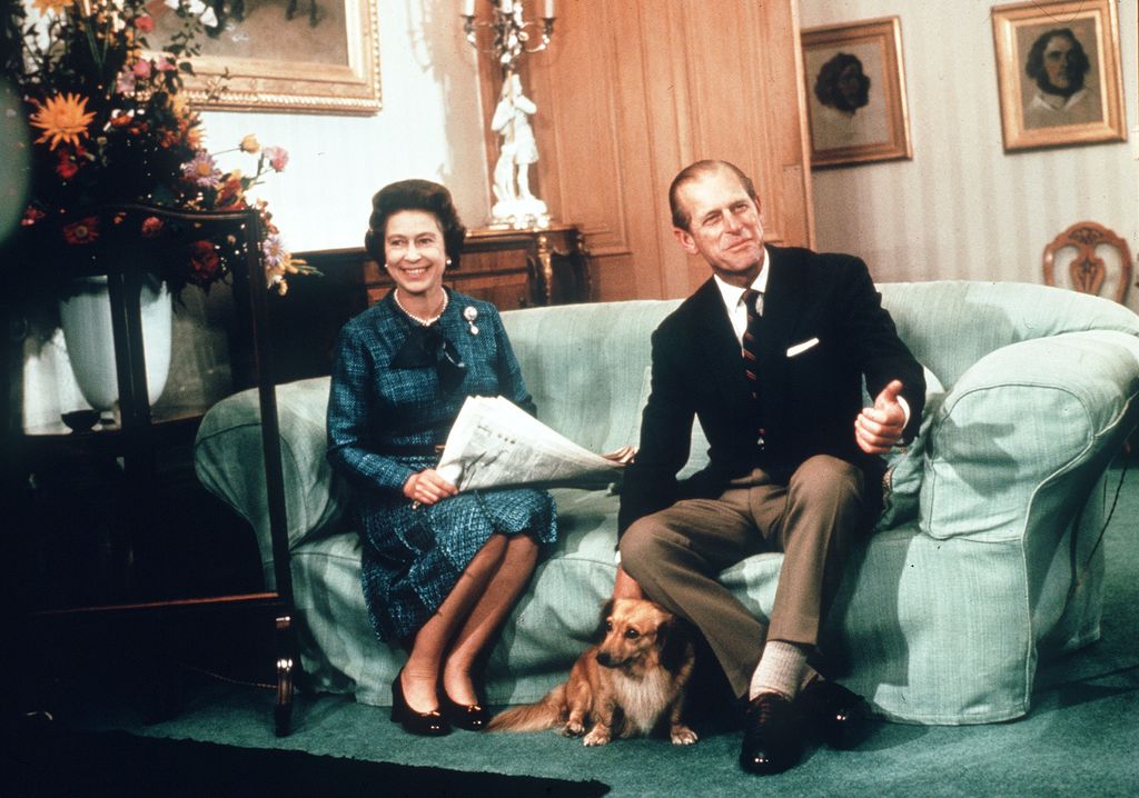couple sat on green sofa with dog at their feet