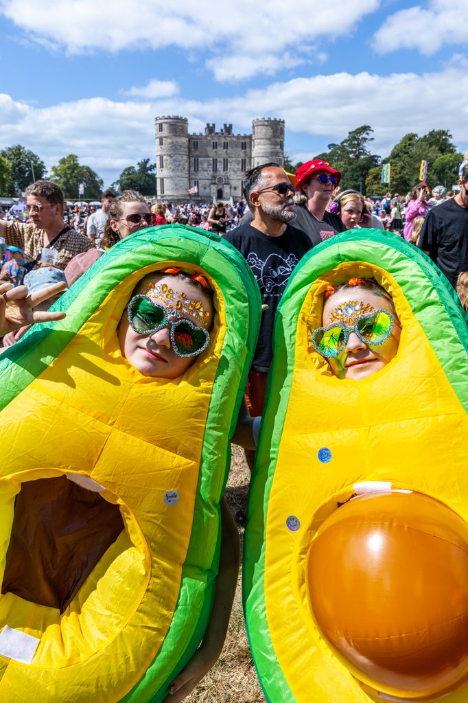 A woman and girl dressed as avocados with people and a castle in the background