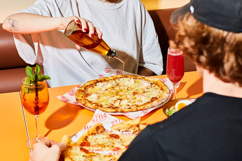 Man pouring sauce onto pizza