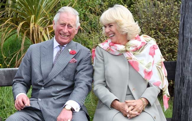 charles and camilla laughing on a bench outside