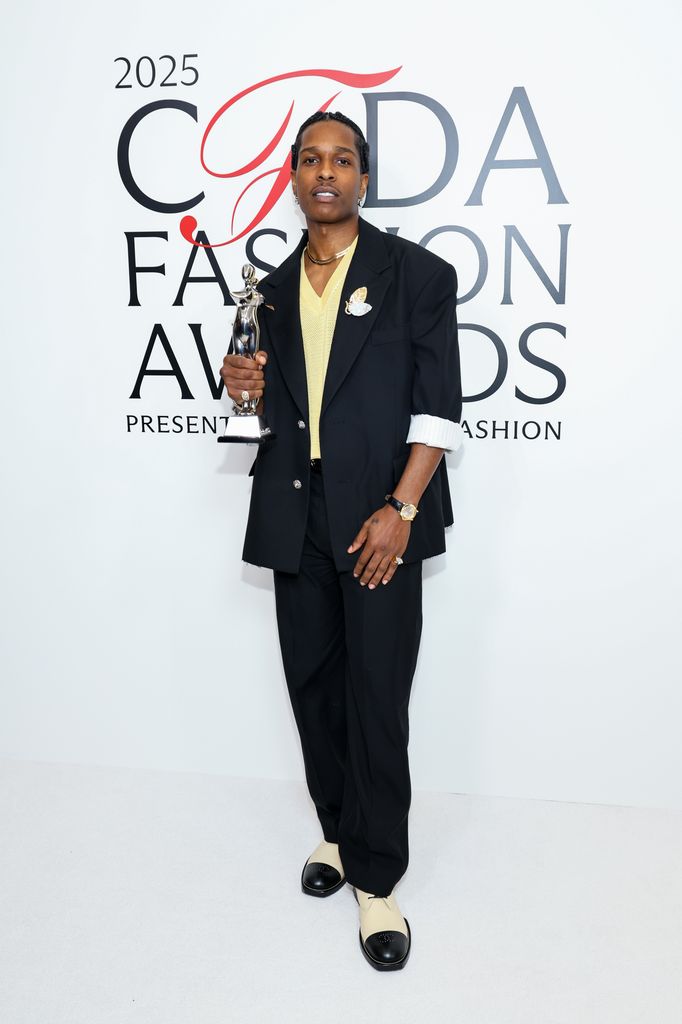 A$AP Rocky poses with the Fashion Icon Award on the red carpet in a black suit