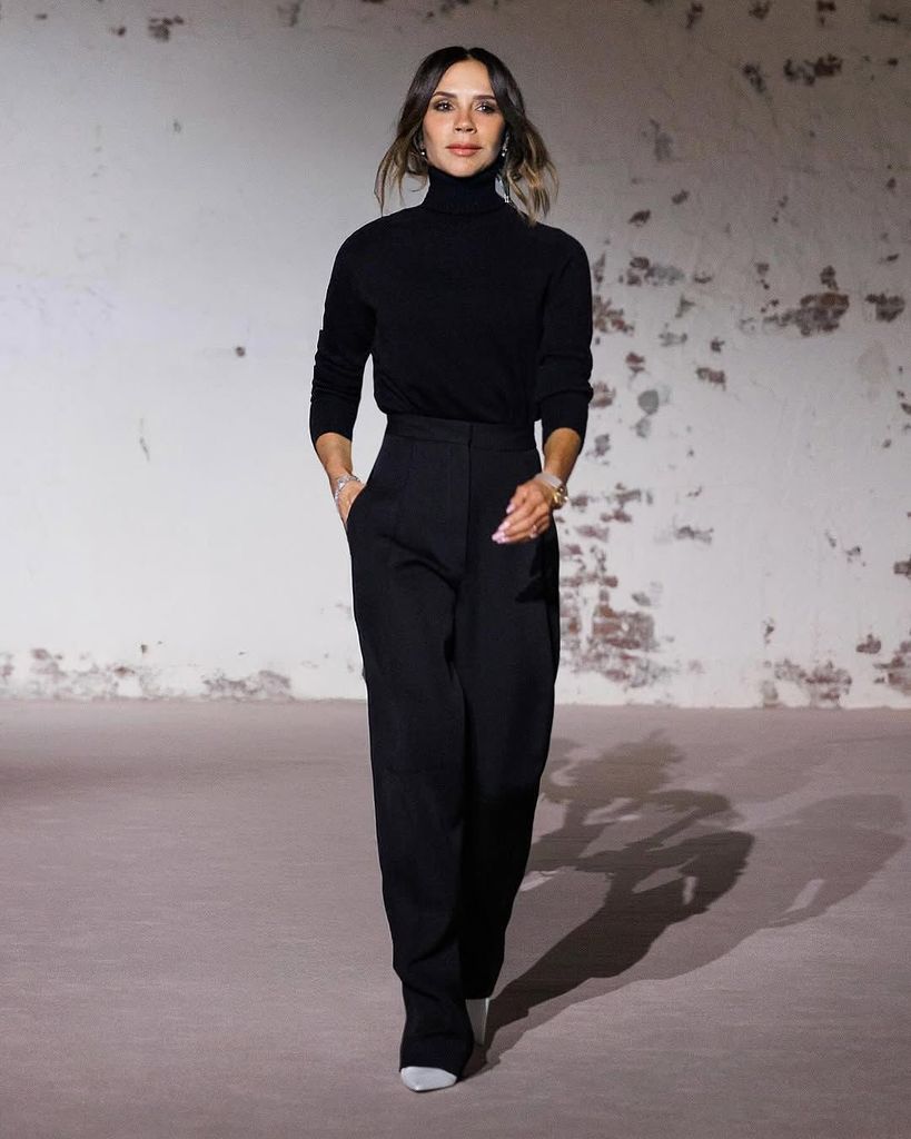 Victoria Beckham berjalan di atas catwalk di All Black