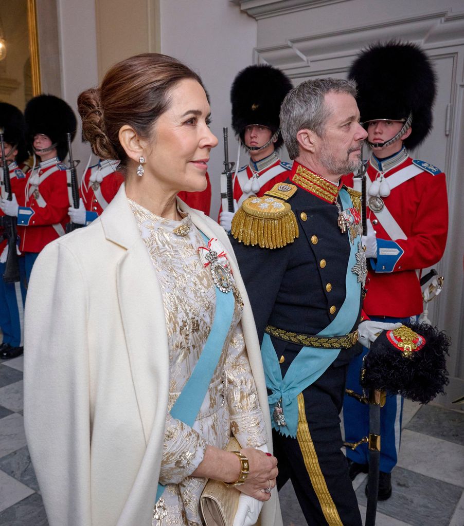 Mary close up in white coat and gold leaf gown beside frederik in uniform