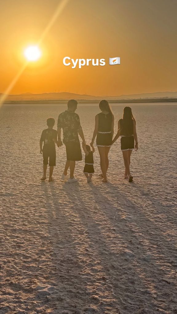 Peter and Emily Andre holding hands with their kids as they walk on the beach