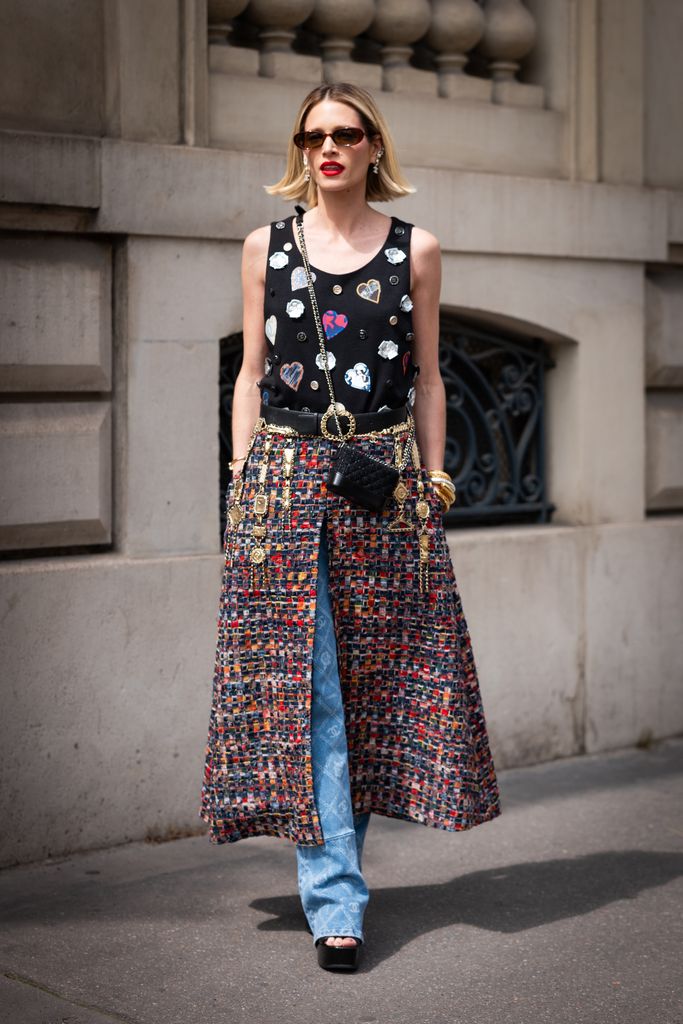 Helena Bordon wears a black decorated Chanel tank top, a Chanel tweed maxi skirt over Chanel jeans, black belt, black Chanel mini bag, black platform heels and Chanel earrings, outside Chanel, during the Haute Couture Fall/Winter 