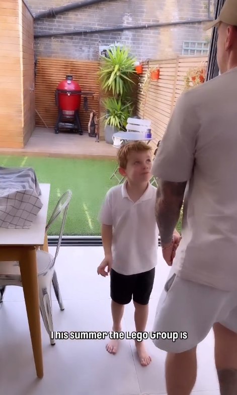 Danny Jones and his son stand in front of the dining area doors with a view out into their garden