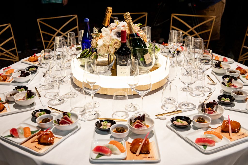 Nobu food sits on 12 places at a table at the Beverly Hilton Hotel as part of a prevoew of the Golden Globe Awards. The centre of the table has a floral arrangement and Moet champagne.