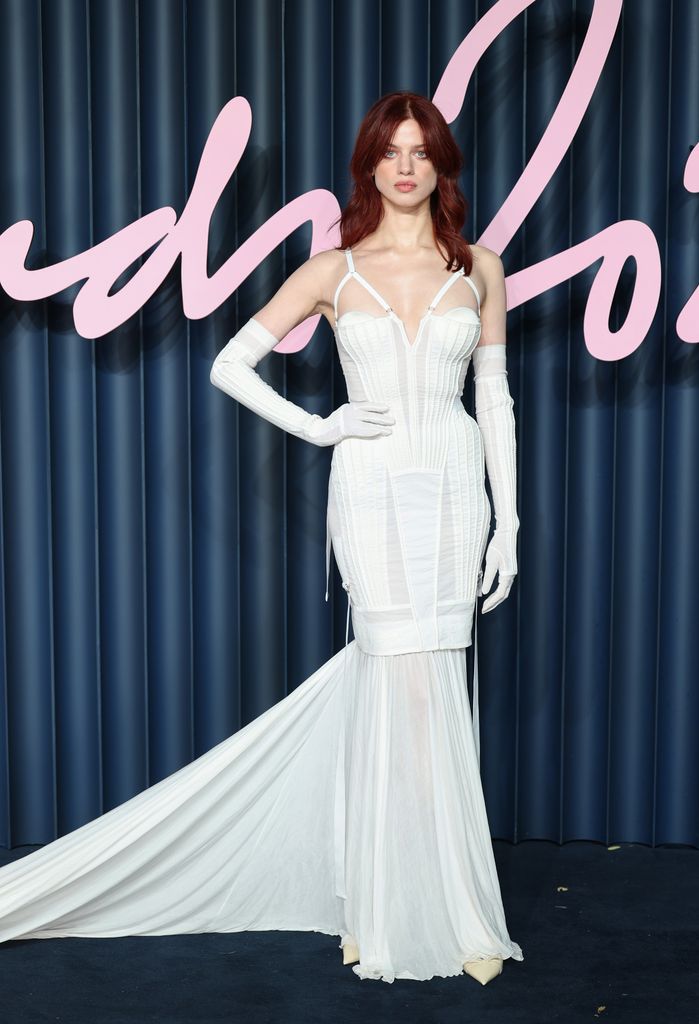 Lily McMenamy wears a white corset dress with long gloves