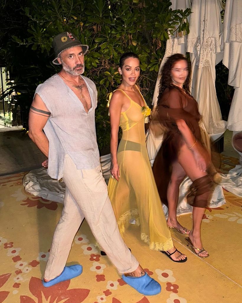 Rita Ora wearing a yellow dress and walking with her husband Taika Waititi
