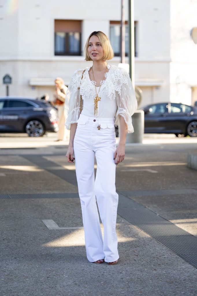 Princess Olympia stuns in a sheer lace blouse, layered necklaces and high-waisted white trousers while attending a Paris fashion event.