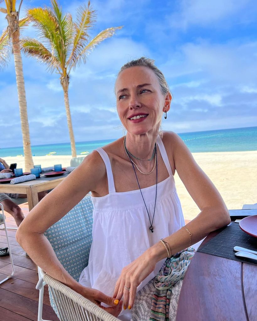 Naomi Watts wearing a white top on the beach with a diamond ring on her left hand