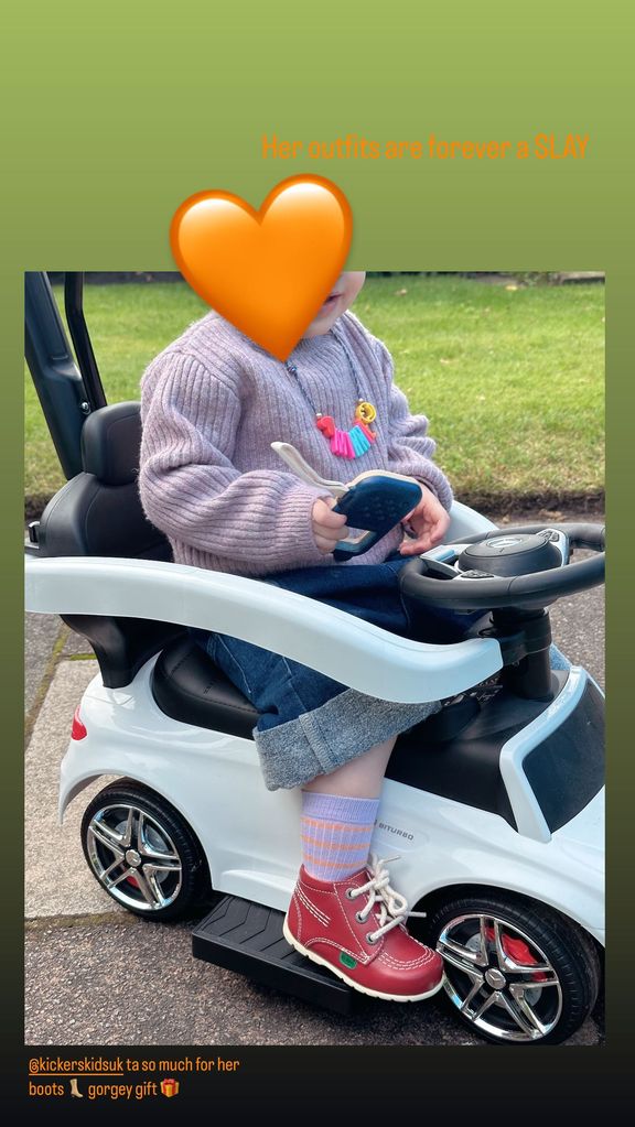 Stacey's daughter Minnie on toy car with face obscured