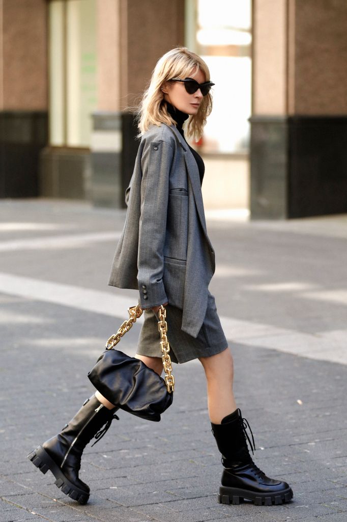  Influencer Gitta Banko, wearing a black turtleneck pullover by Liviana Conti, an asymmetrical grey blazer and matching grey bermuda shorts by Balossa, sunglasses by Mykita x Maison Margiela, a black chain pouch bag by Bottega Veneta 