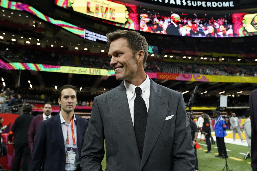 Retired football player and Fox analyst Tom Brady walks the sidelines before the start of Super Bowl        
