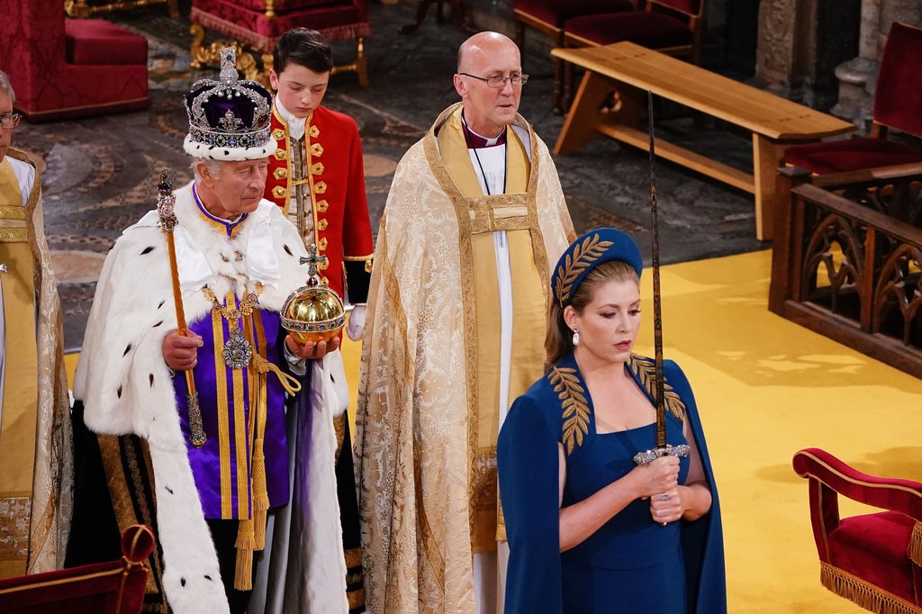 Penny Mordaunt holding the Sword of State walking ahead of King Charles III during the Coronation