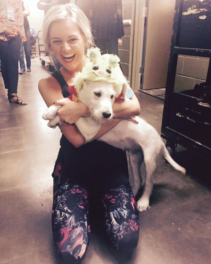 Kelsea Ballerini kneels on the floor with her dog Dibs when he was a puppy