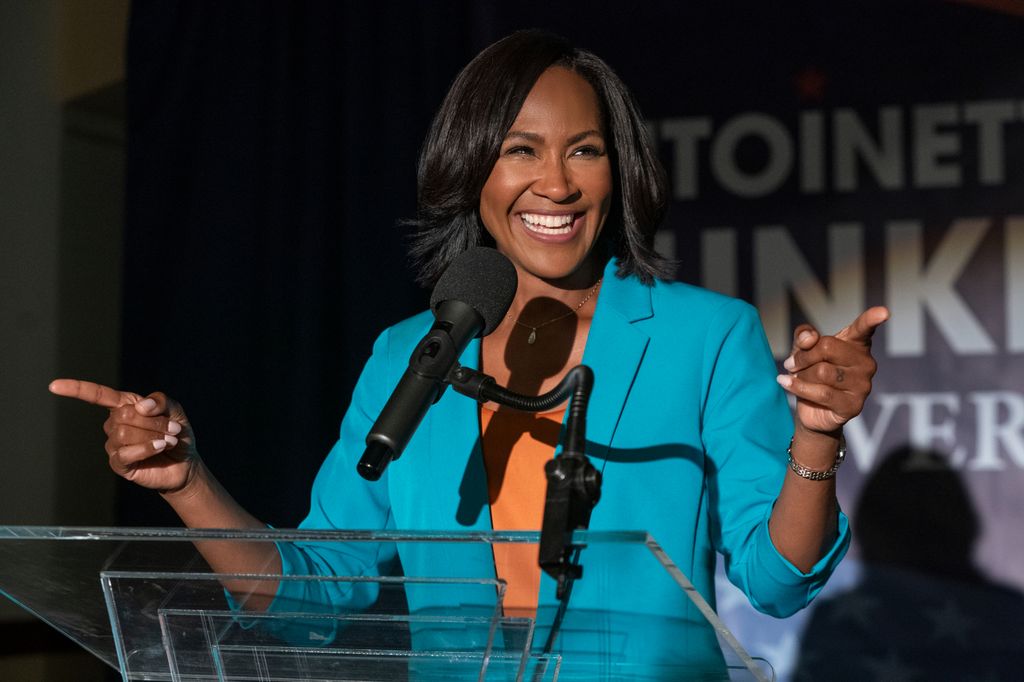 woman in blue suit speaking into microphone on stage