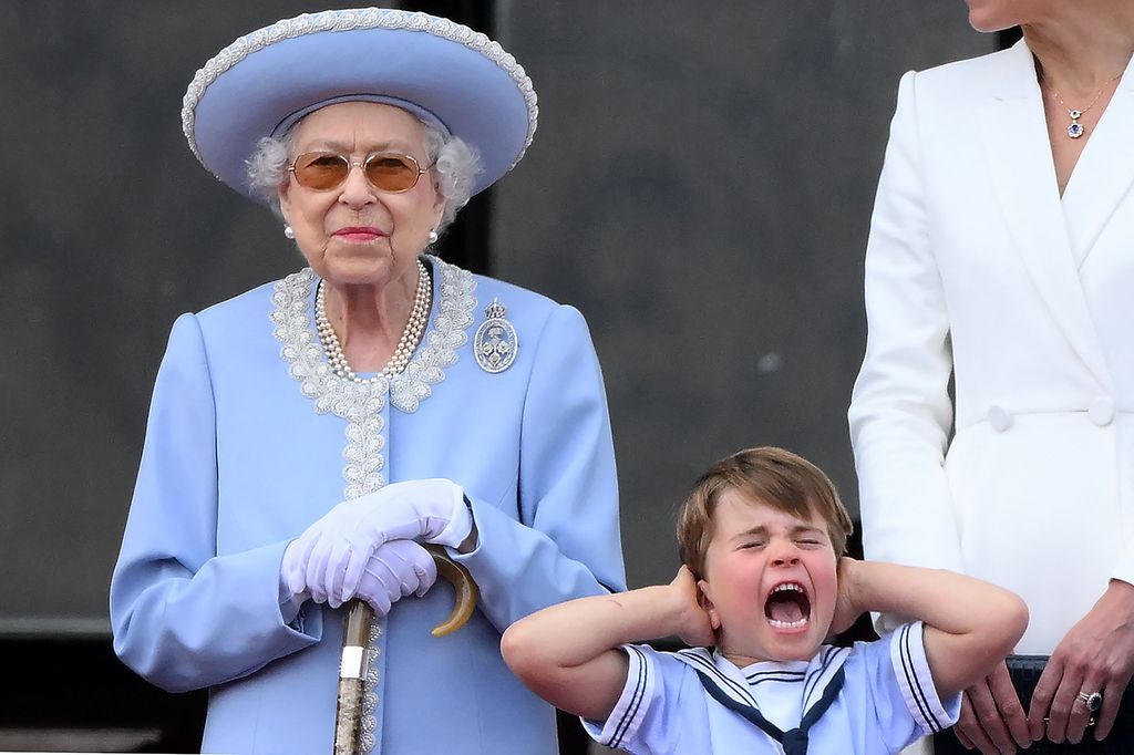 Prince Louis shouting and covering his ears while standing next to the Queen