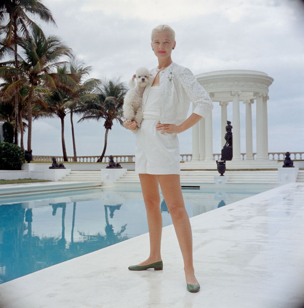 C.Z. Guest holding poodle poolside in New York, 1962
