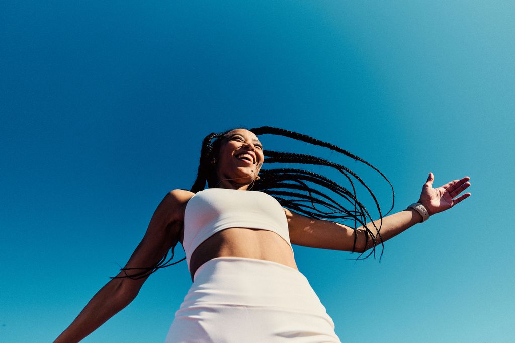 Attractive athletic woman wearing white sports clothing with arm out, view from below