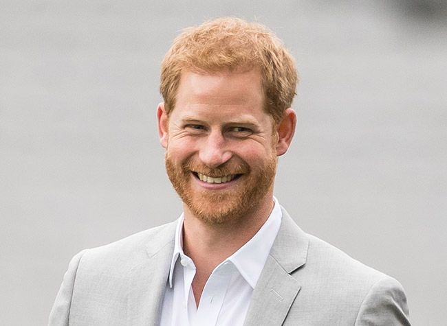 Prince Harry smiling in a grey suit