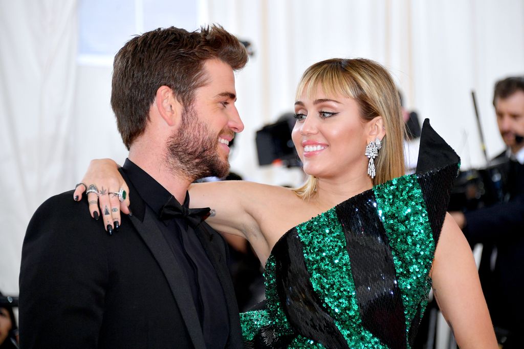 Liam Hemsworth with Miley Cyrus wrapping her arm around him