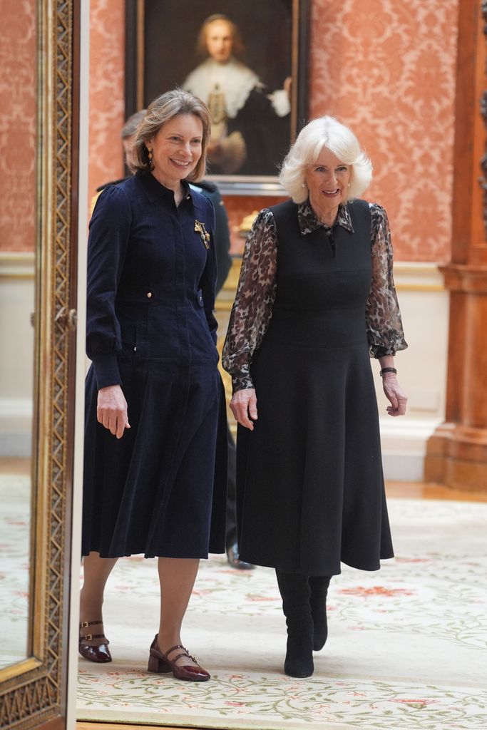 Rainha Camilla no Palácio de Buckingham com vestido preto e blusa transparente com estampa de leopardo