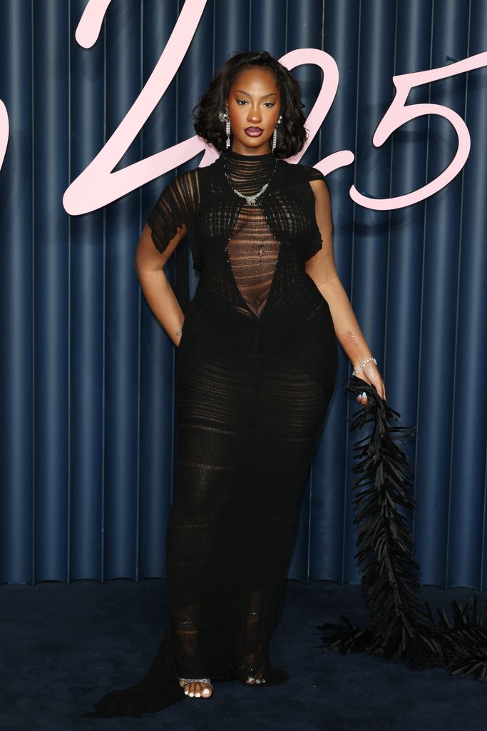 Tems wears a black knitted dress with short sleeves and fraying sheer fabric