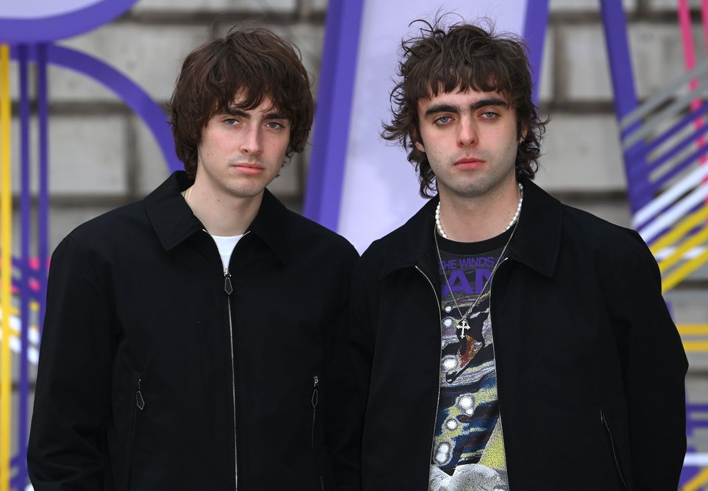 Gene Gallagher standing with Lennon Gallagher in black jackets