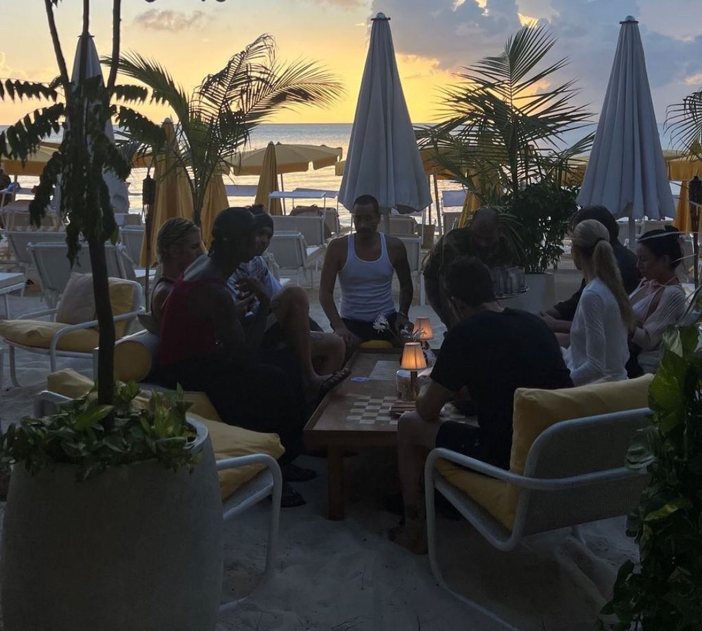 group of people eating dinner outside on the beach