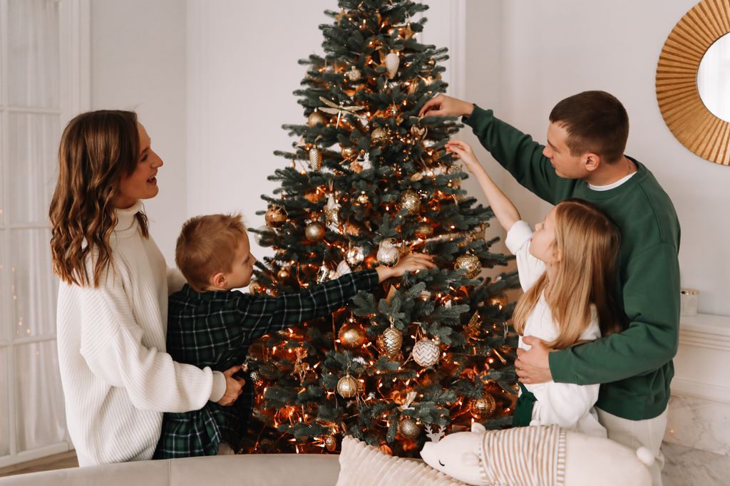 A family with two teenage children in casual clothes have fun together and celebrate the Christmas holiday