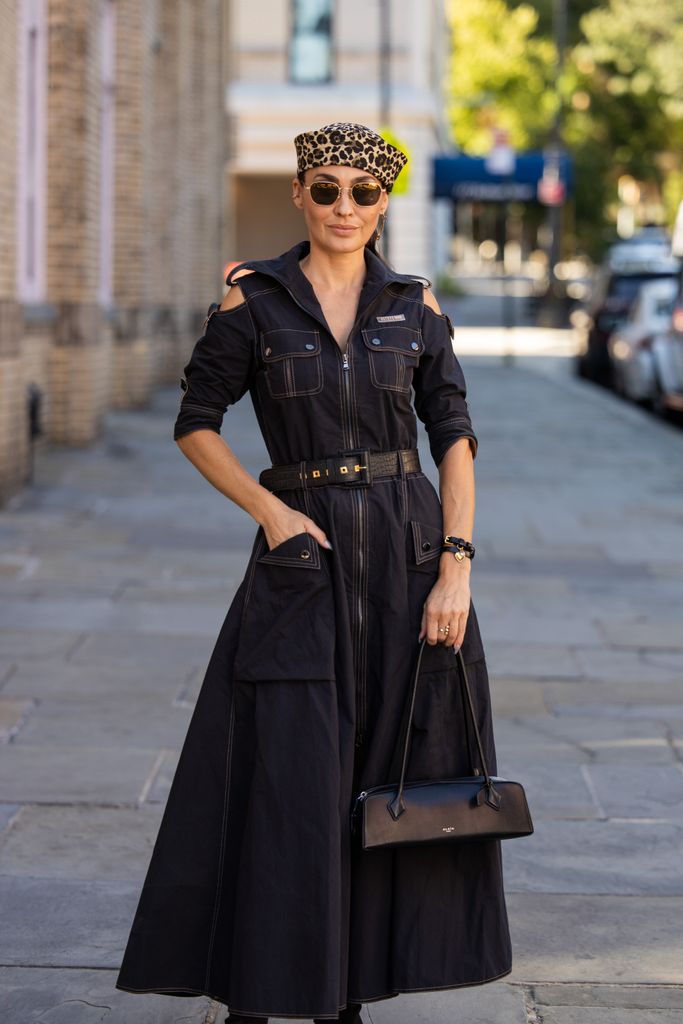 Yana Echko wears black cut out belted zipper dress, Alaia bag, leopard print hat, sunglasses during New York Fashion Week on September 11, 2024 in New York City.