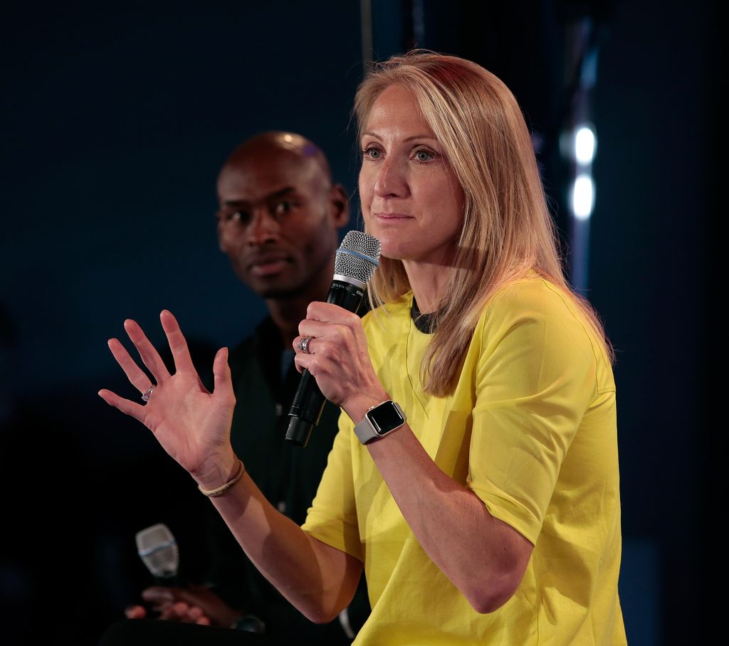 woman speaking into microphone wearing yellow top 
