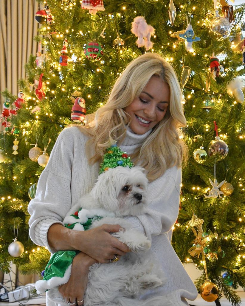 Tess Daly wears a white polo neck and cuddles a white dog