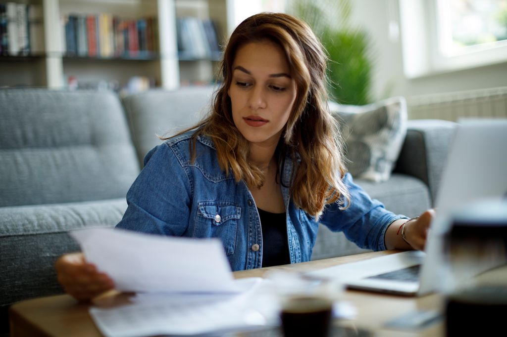 Woman calculating finances at home wearing denim shirt