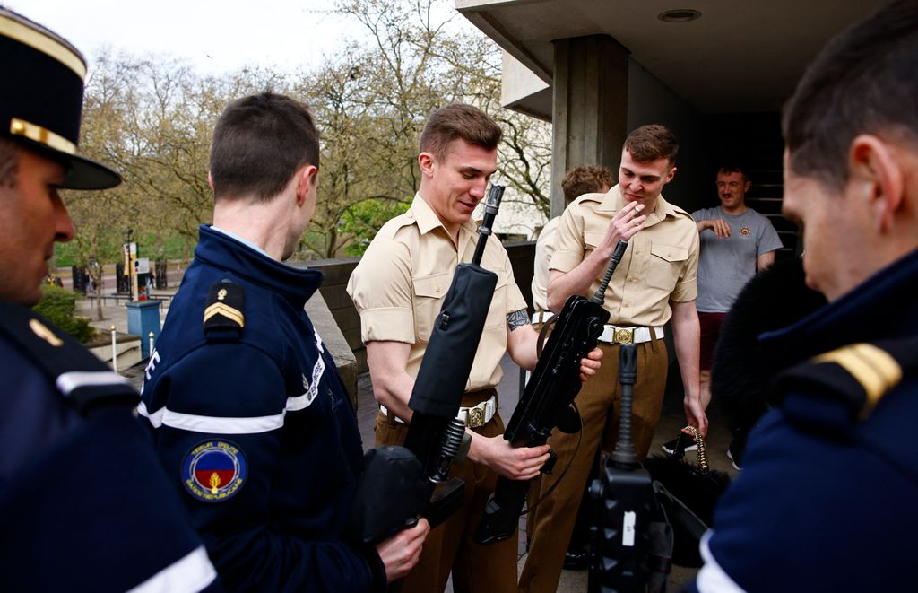 Members of France's Gendarmerie Garde Republicaine and members of the British Army's F Company Scots Guards look at each others' rifles following a rehearsal for a special Changing of the Guard ceremony