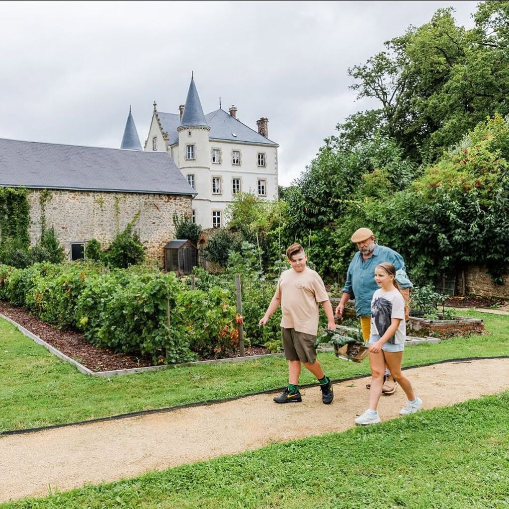 Dick Strawbridge walking through garden with two children Arthur and Dorothy with chateau seen in the background