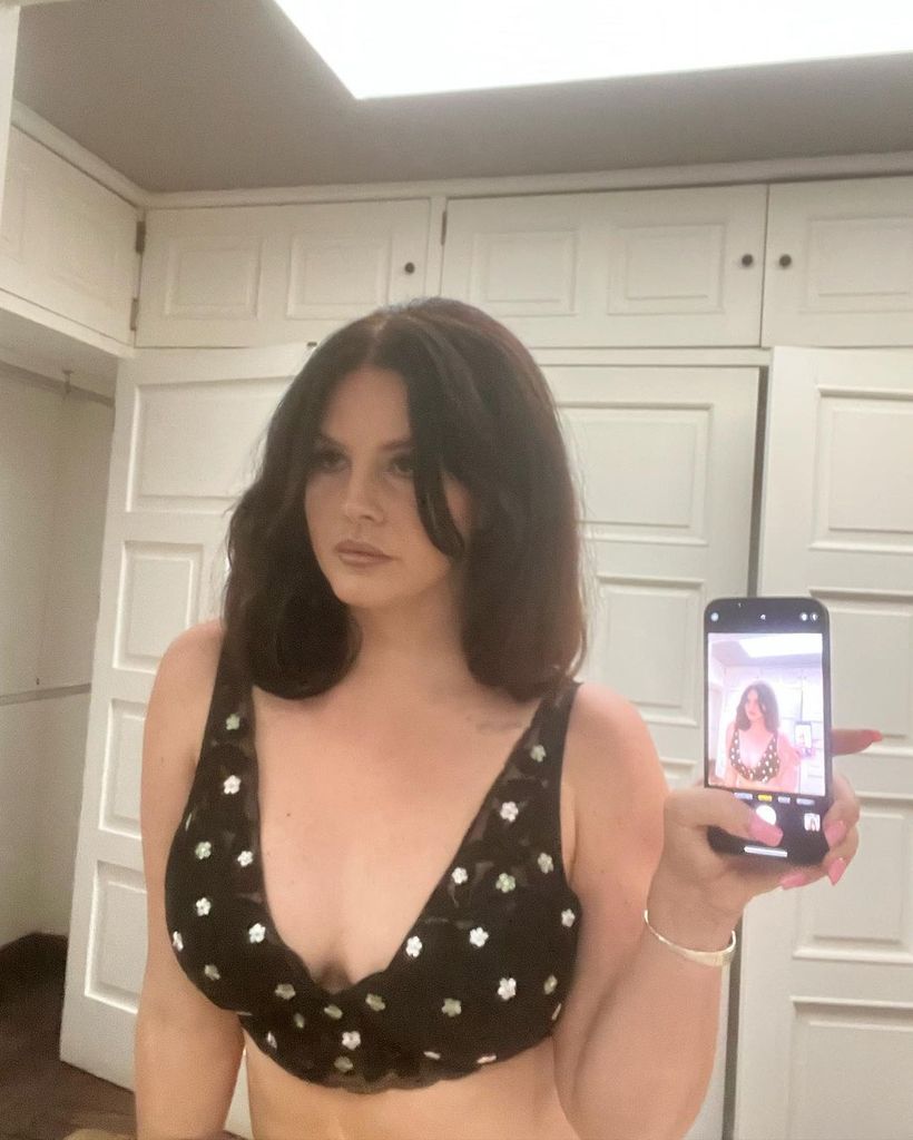 Lana Del Rey wearing black daisy bralette for mirror selfie