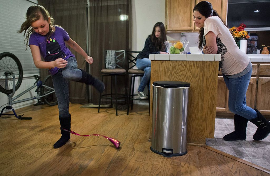L'enfant saute par-dessus un petit rôle attaché à son autre cheville.