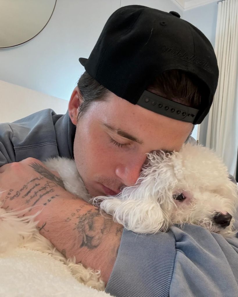 Brooklyn Beckham hugging white dog