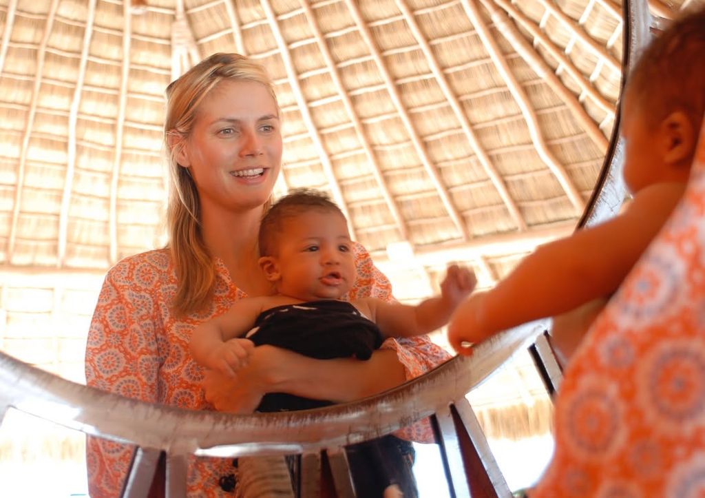 Heidi Klum in orange dress cradling Henry as a baby