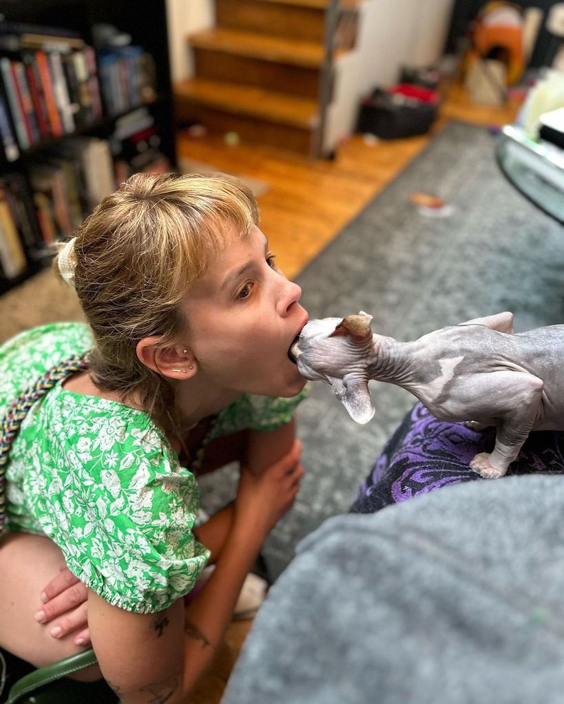 Sosie Bacon opens her mouth and her cat puts its head inside