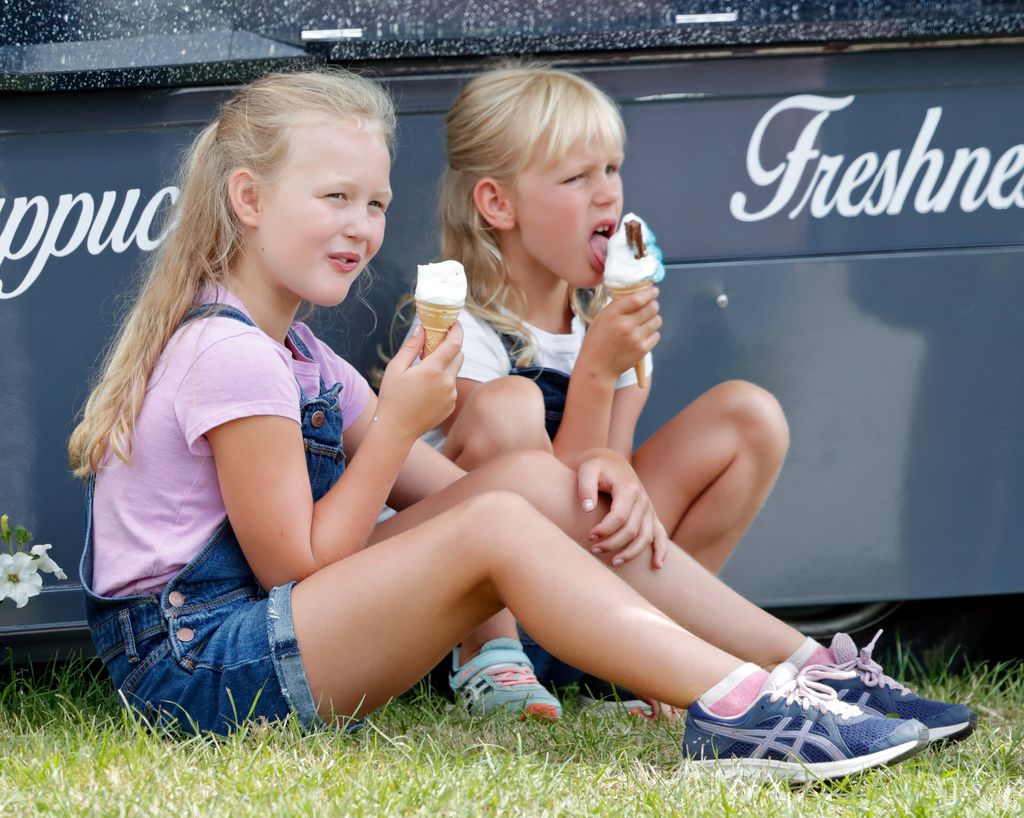 Savannah Phillips and sister Isla Phillips eat ice cream sat in field