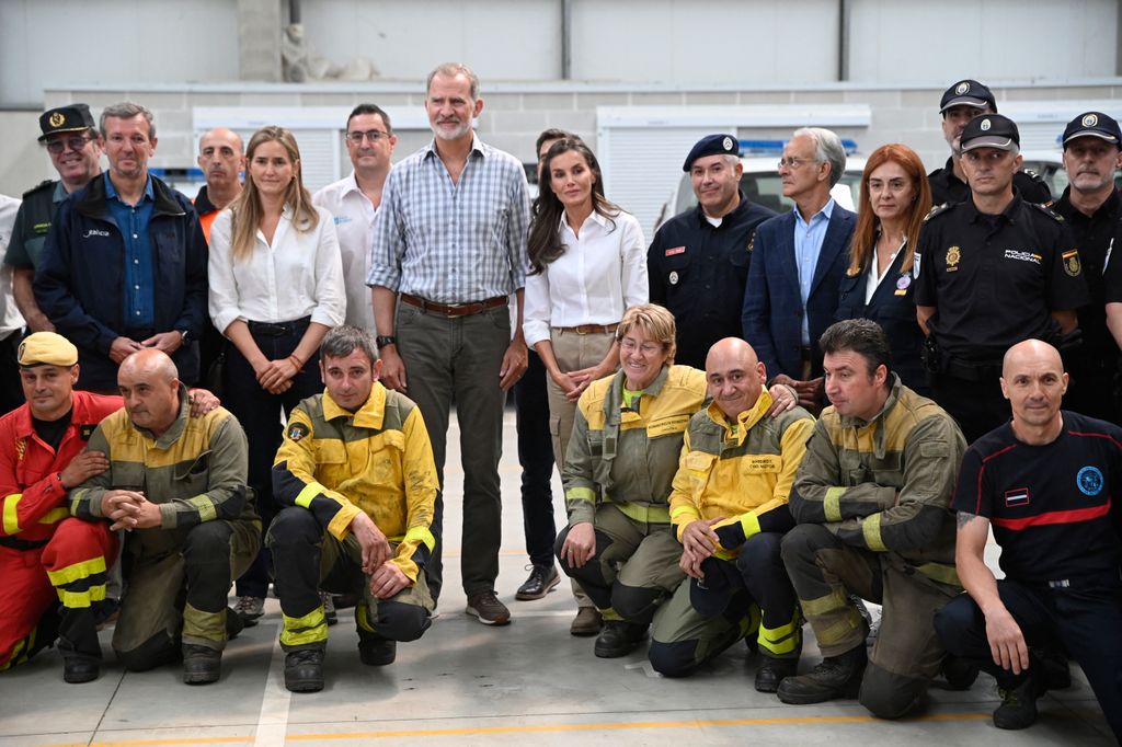 Spain's King Felipe VI (CL) and Queen Letizia (CR) pose for a family photo with officials of the emergency services after arriving in Verin, northwestern Spain,
