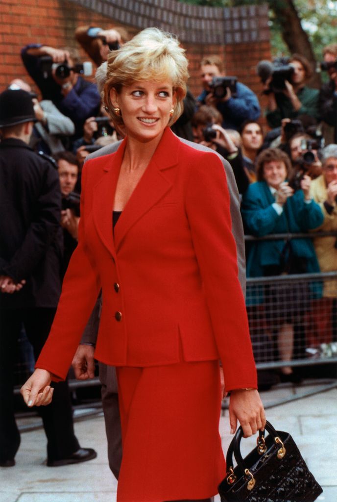 Princess Diana in the 90s wearing a red suit and carrying a black Lady Dior bag