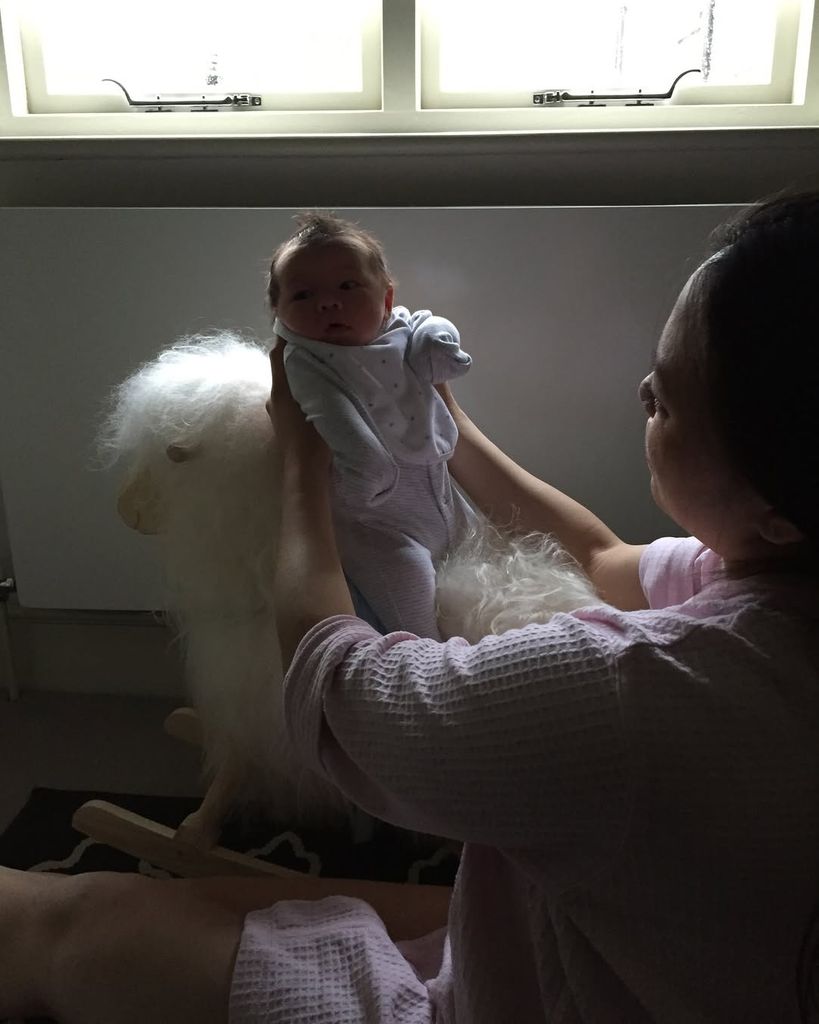 Dara Huang holding baby Wolfie up on a rocking horse