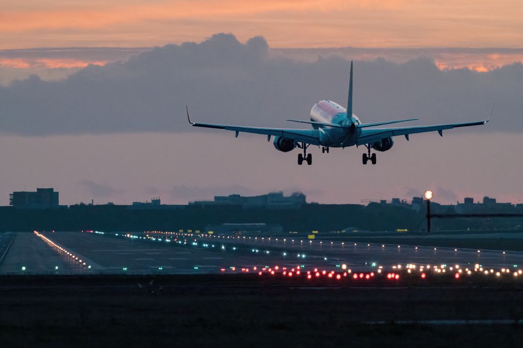 Landing in sunset hues, airplane landing at sunrise.